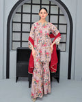 Woman in a floral dress with a red shawl standing in front of an archway.