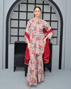 Woman in a floral dress with a red shawl standing in front of an archway.