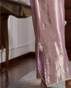 A close-up of a person wearing a lavender satin garment with silver embroidered swirl patterns and a silver beaded trim along the hem, standing in an indoor setting.
