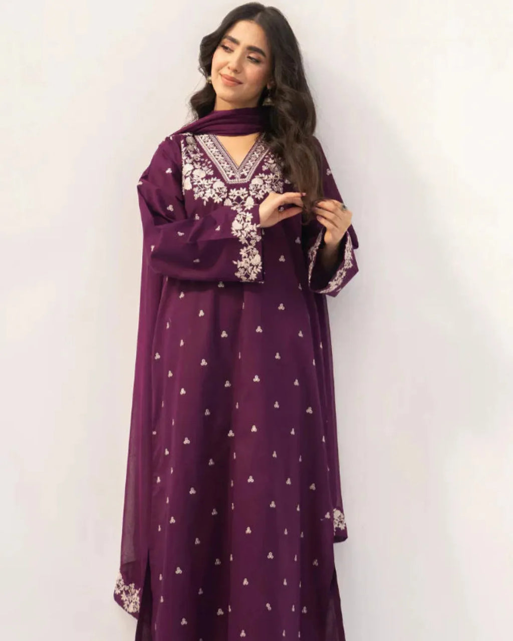 Woman wearing a purple dress with white patterns against a white background