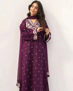 Woman wearing a purple dress with white patterns against a white background