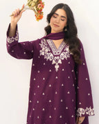 Woman wearing a purple embroidered dress holding flowers against a white background