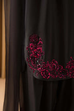 Black fabric with red floral embroidery on a plain background
