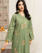 Woman wearing a green embroidered dress with a neutral background