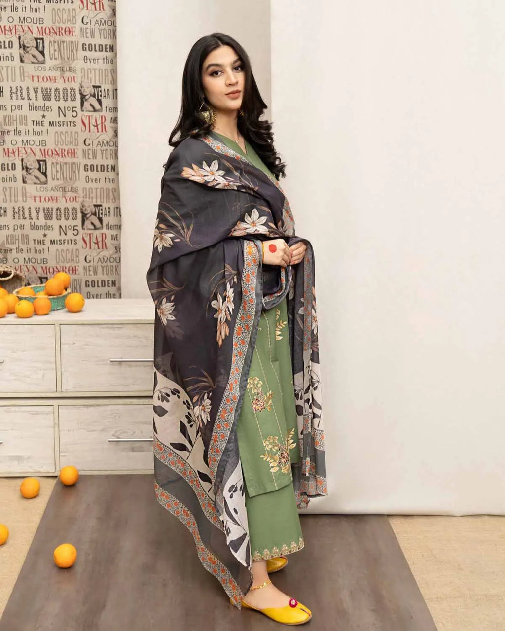 Woman in a traditional outfit standing in a room with decorative elements.