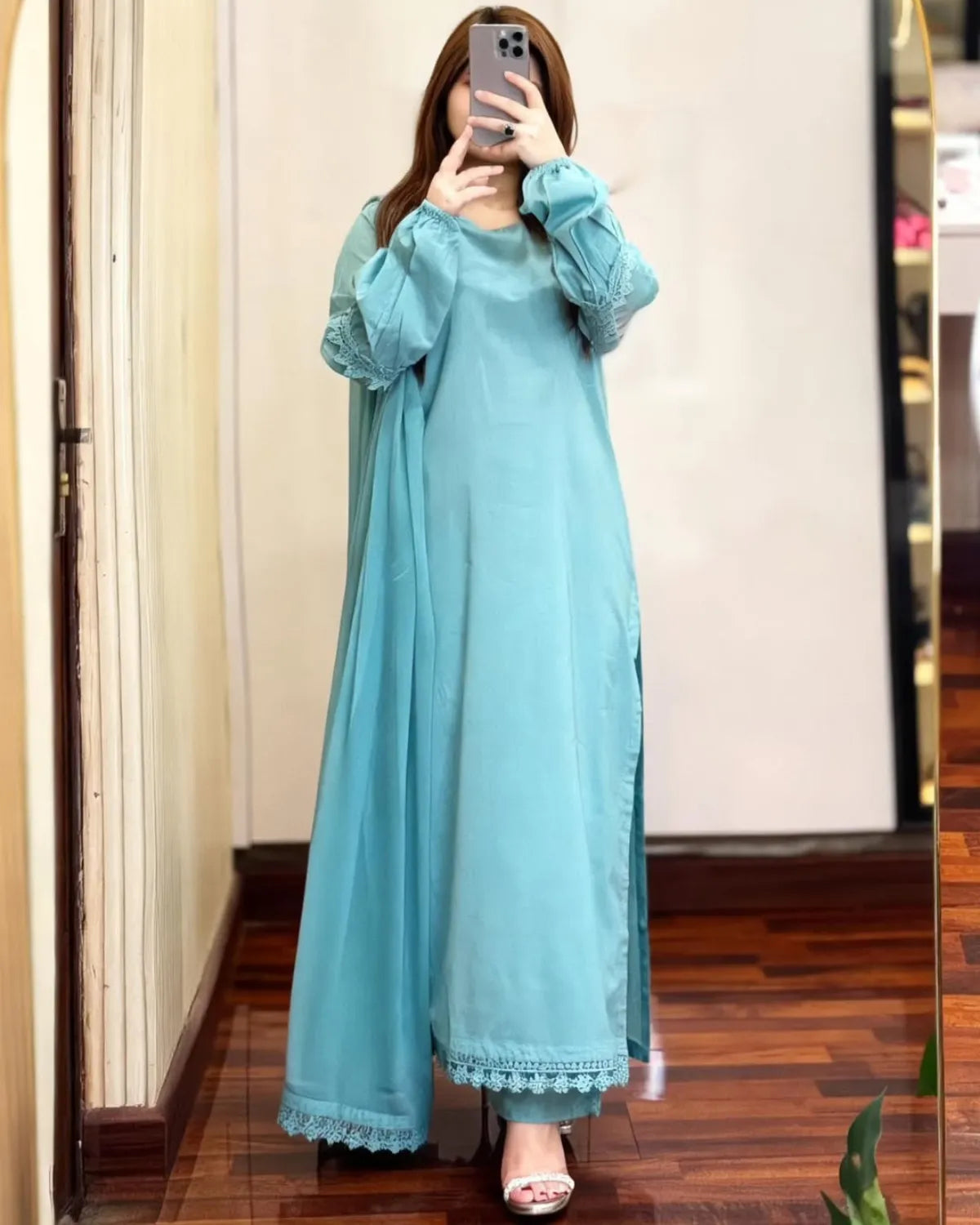 Person wearing a light blue dress with lace details, standing in front of a mirror.