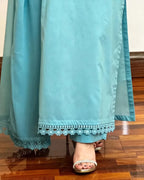 Teal outfit with white lace trim on a wooden floor