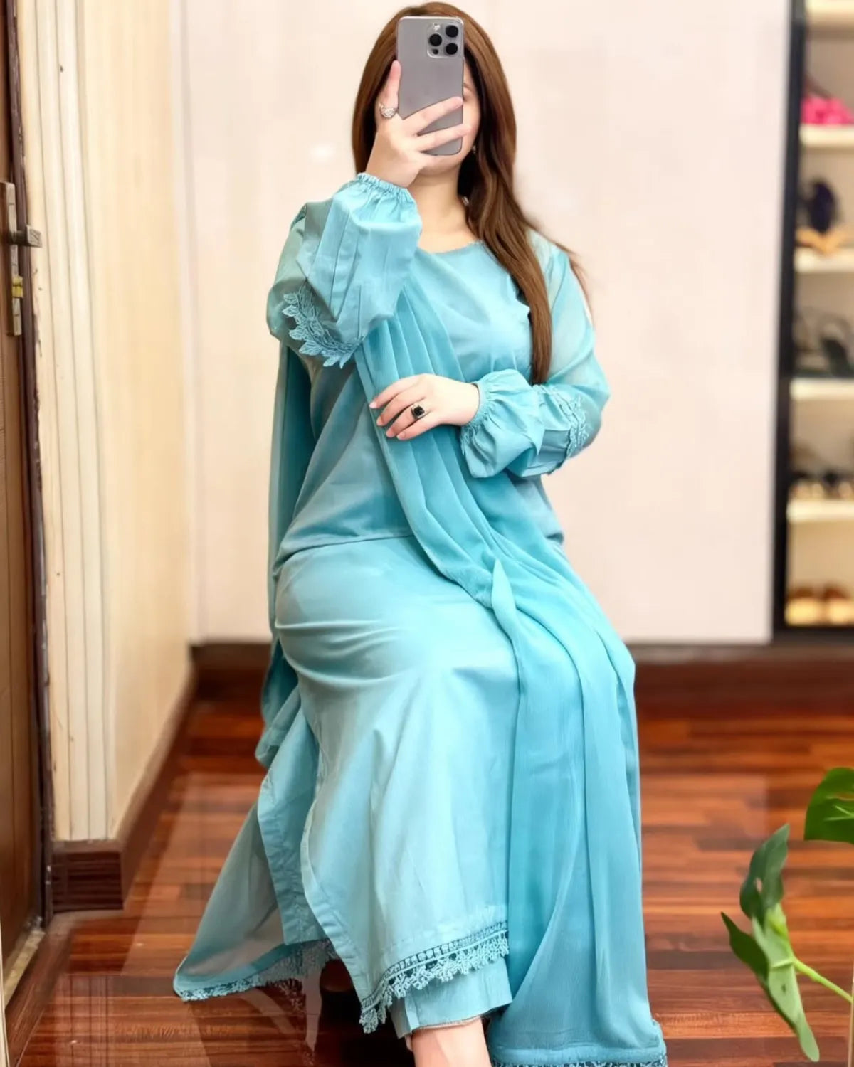 Woman wearing a light blue dress with long sleeves in a room.