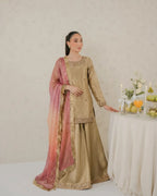 Woman in a traditional outfit with a pink dupatta standing next to a table with fruits and candles.