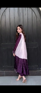 Woman wearing a purple and white traditional outfit against a dark background