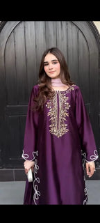 Woman wearing a purple embroidered dress against a dark background