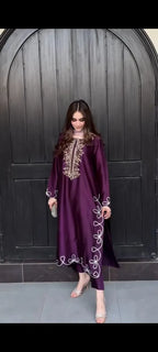 Woman wearing a purple embroidered dress against a dark background