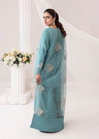 Woman wearing a teal embroidered outfit with a white background