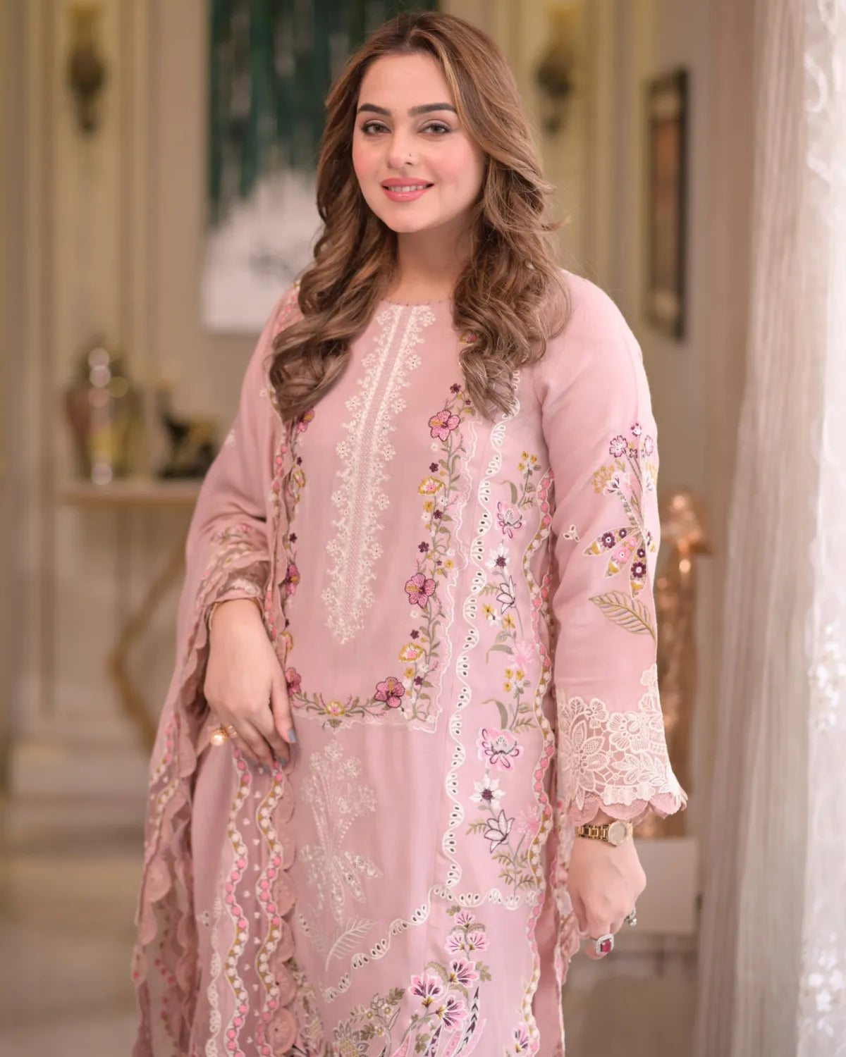 Woman wearing a pink embroidered outfit in an indoor setting