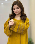 Woman wearing a yellow outfit with intricate designs, indoors.