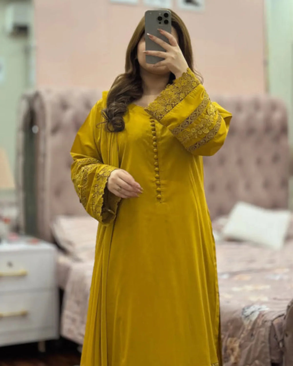 Person wearing a yellow dress with intricate detailing in a bedroom setting