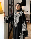 Woman wearing a black embroidered dress in an indoor setting