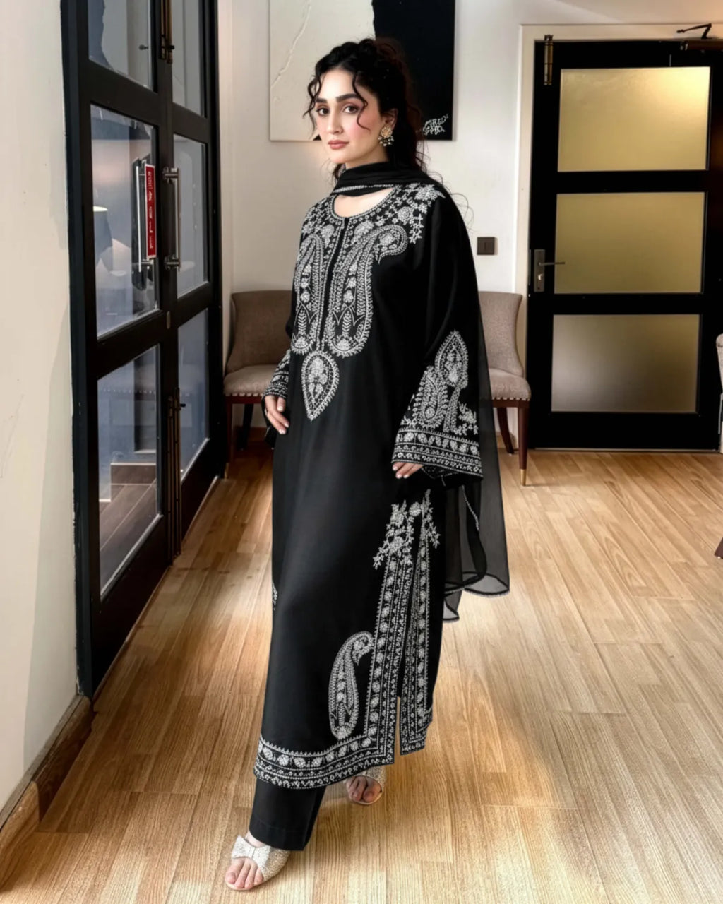 Woman wearing a black embroidered outfit in an indoor setting.