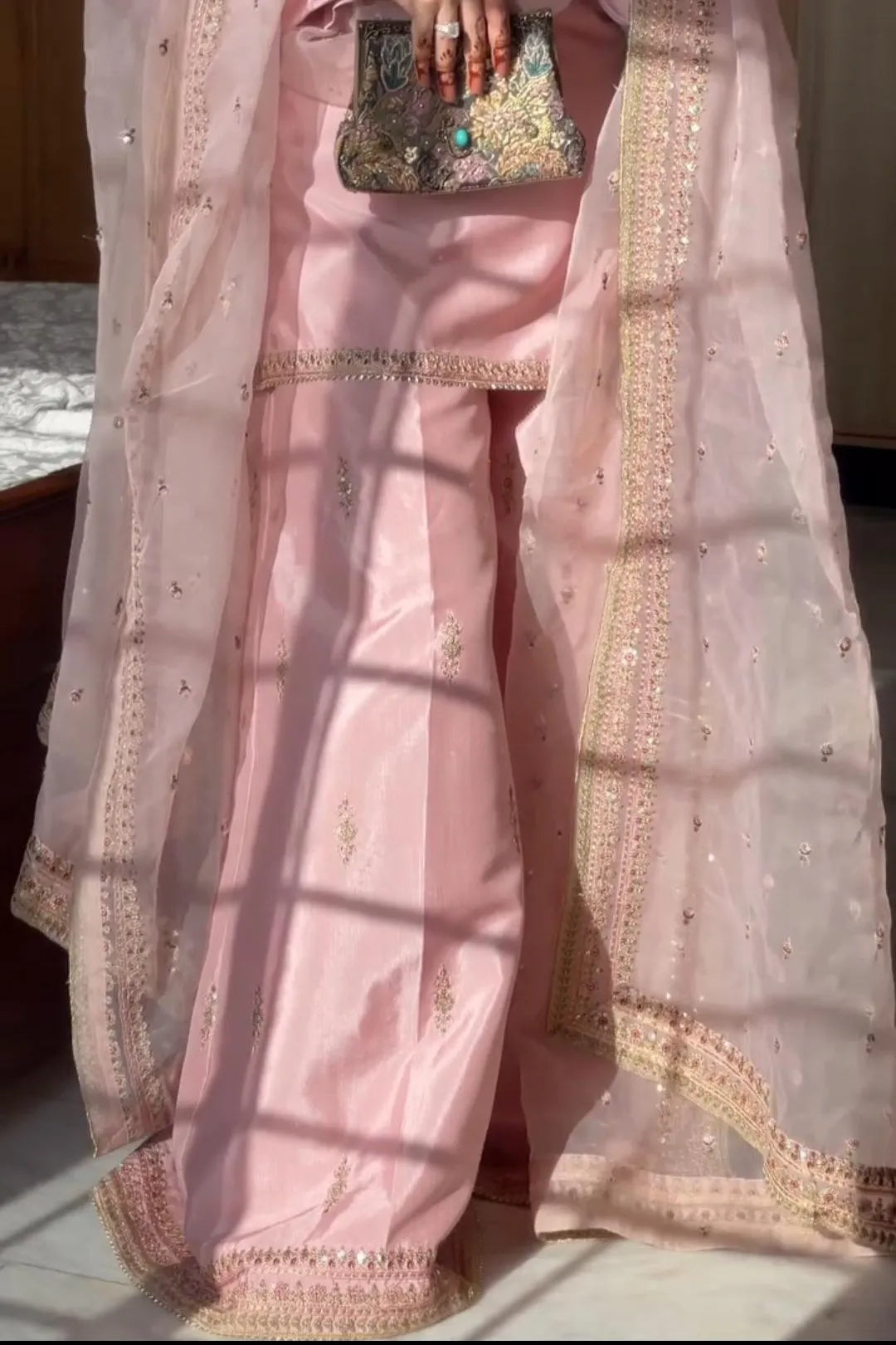 Pink traditional outfit with a dupatta draped over it, held by a hand.