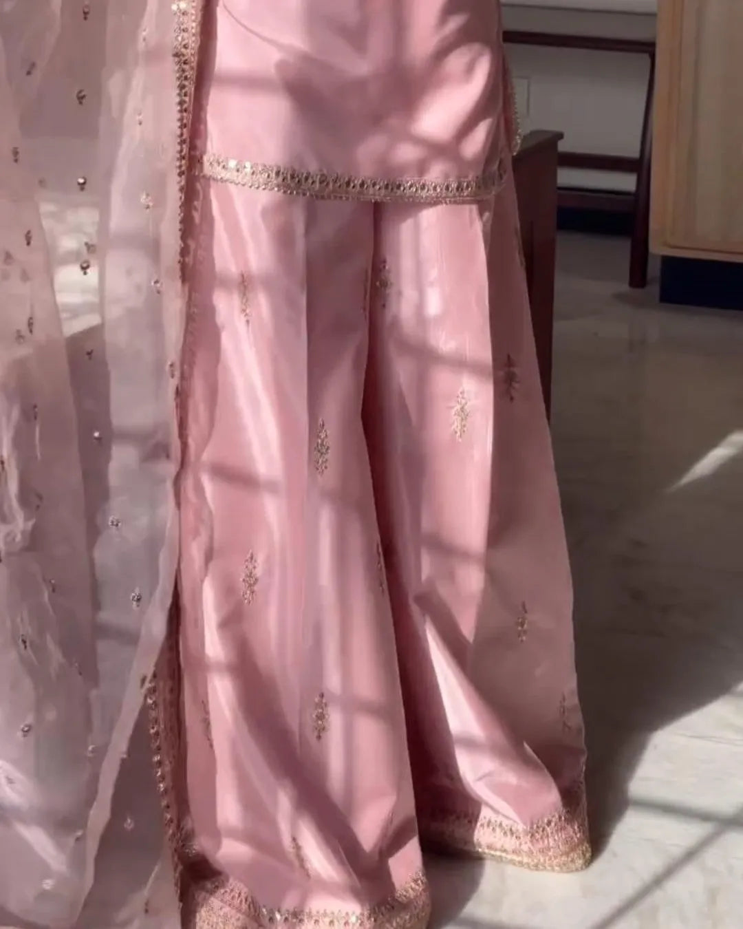 Pink traditional outfit with gold embroidery on a light background