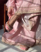 Person wearing a pink traditional outfit with intricate designs and sandals.